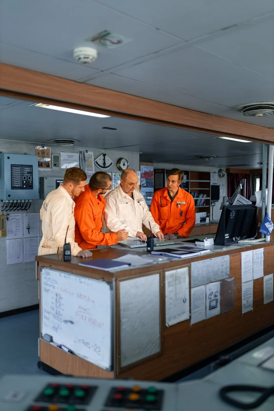 A team of marine professionals conducting a TMSA 3 consultancy review of ship documents on the vessel's bridge.