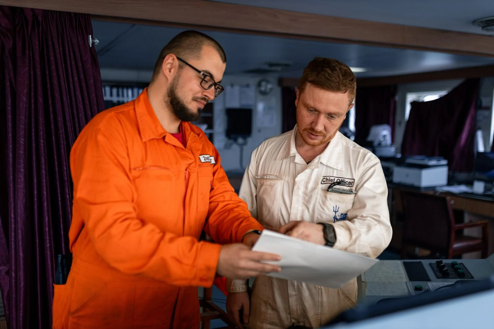 A Chief Officer and 2nd Engineer reviewing operational documents on a vessel — commercial and technical teams coordinating during voyage execution.